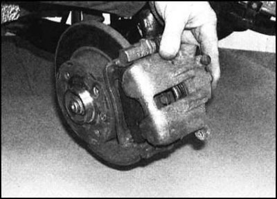 4. Повернув суппорт вверх, снимите его с колодок…